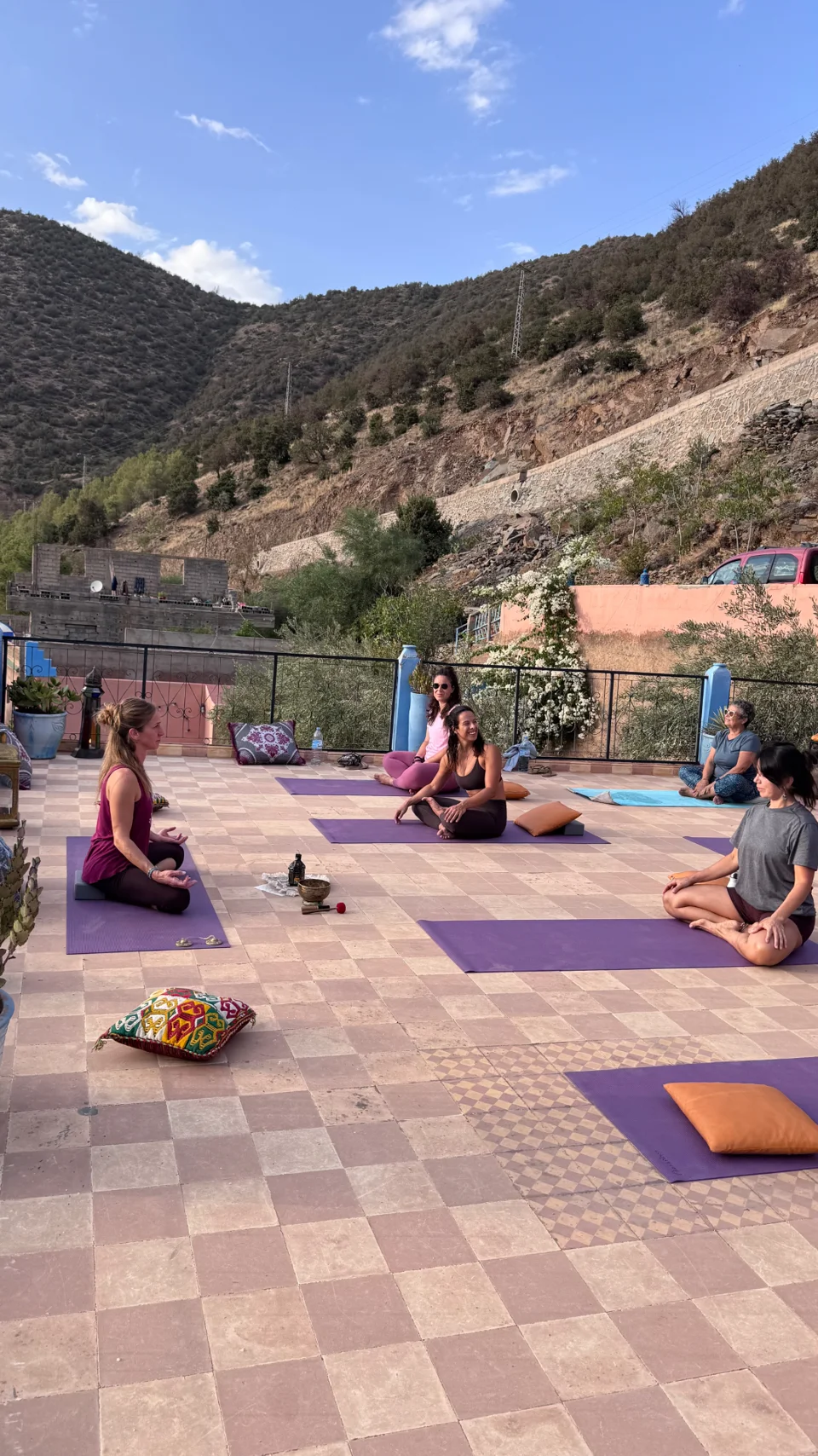 Yoga circle seated on mats on the terrace with the teacher and singing bowl
