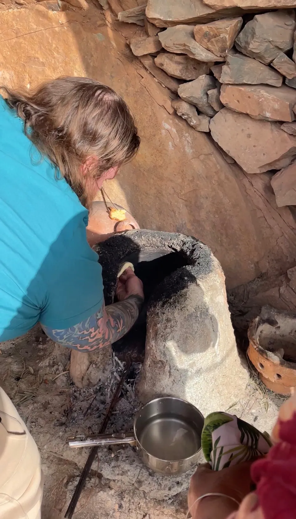 A guest pressing dough onto the hot wall of the traditional clay oven