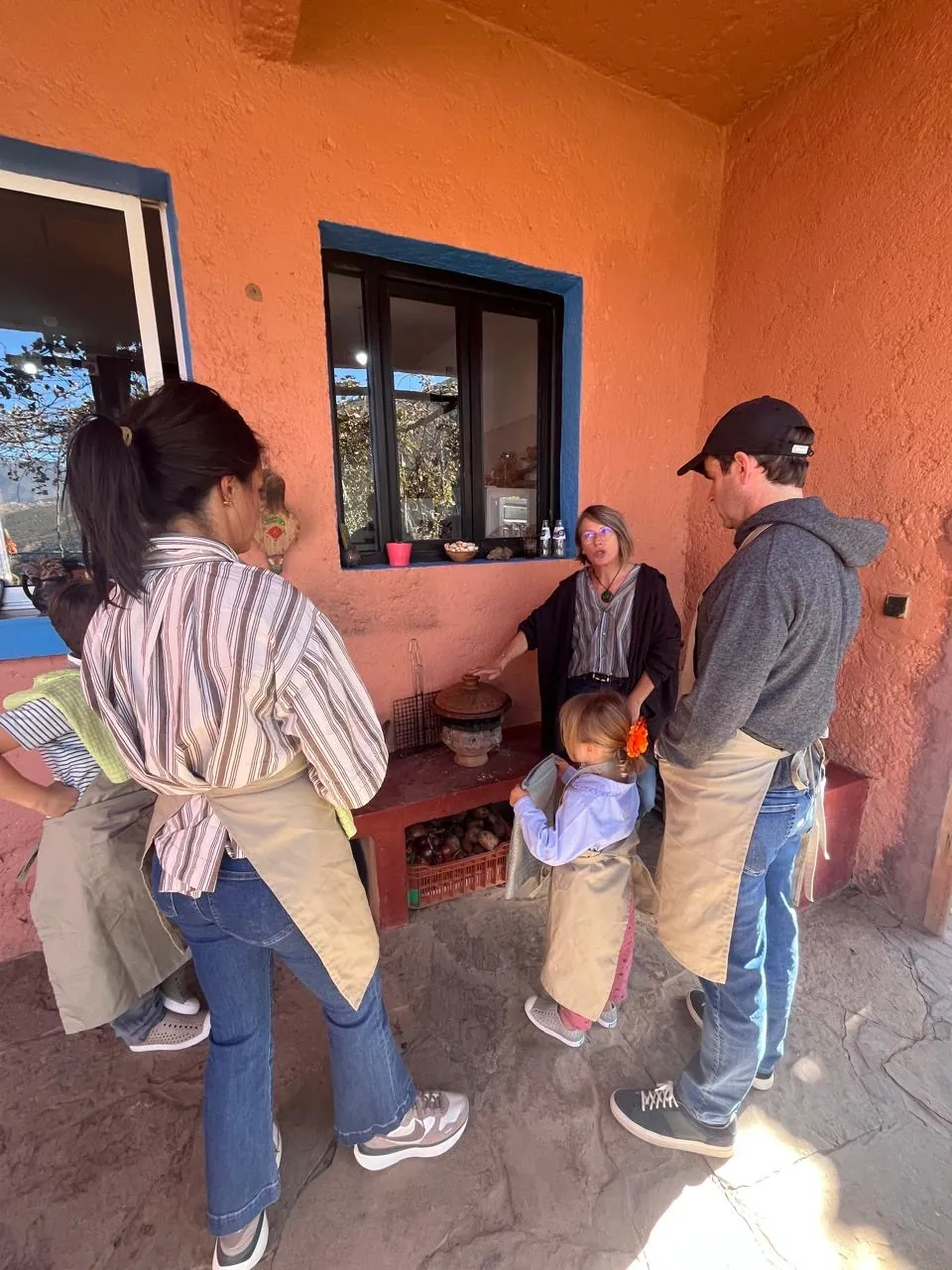 The workshop starting in the courtyard, guests listening beside the traditional stove