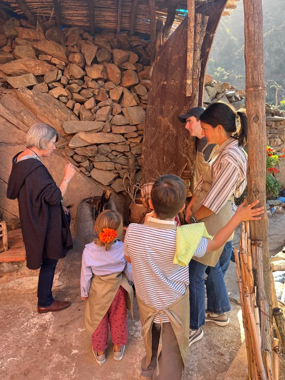 Guests in aprons gathered around the clay oven as bread bakes