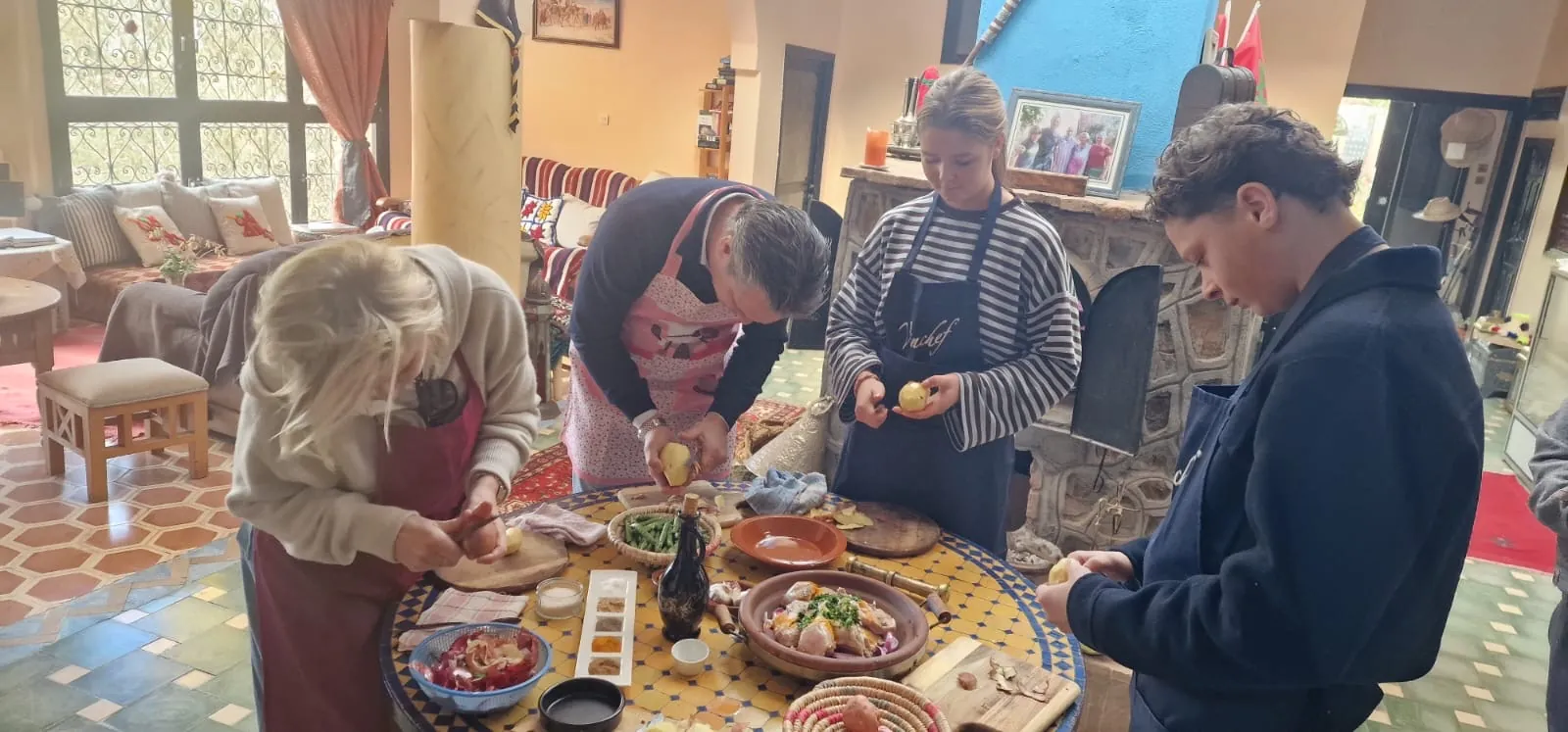 Guests peeling and chopping vegetables around the mosaic table for the tagine