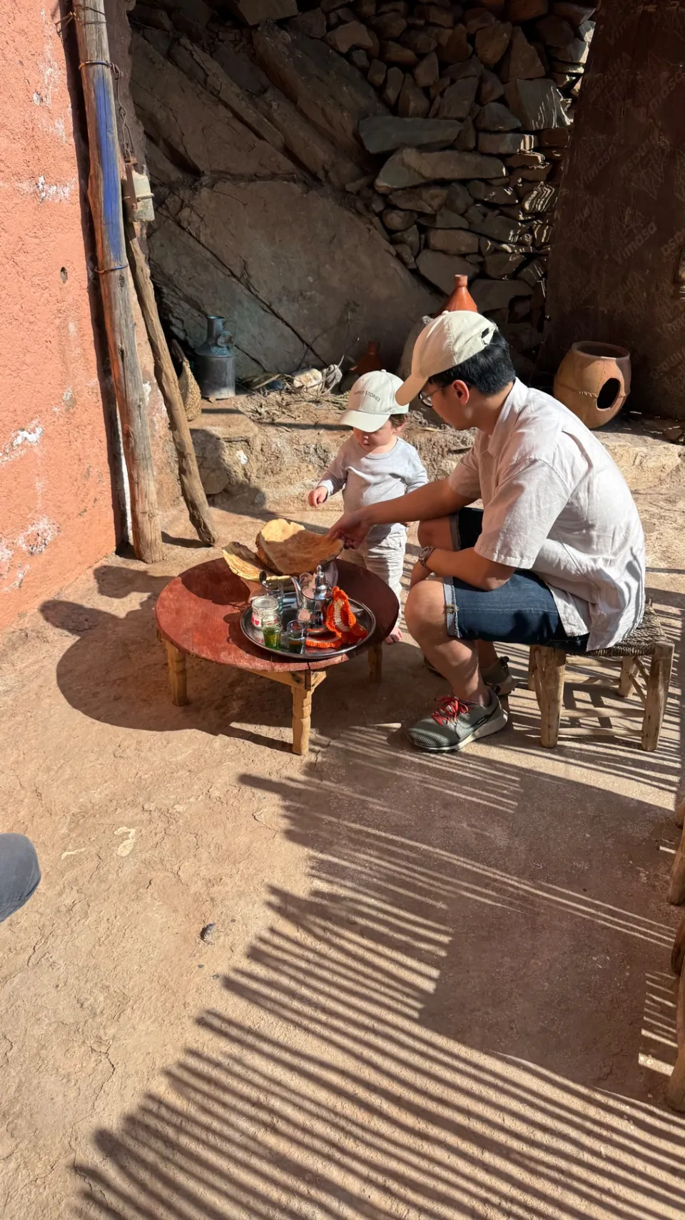 Thé à la menthe et pain chaud partagés sur une table basse dans une cour de village ensoleillée