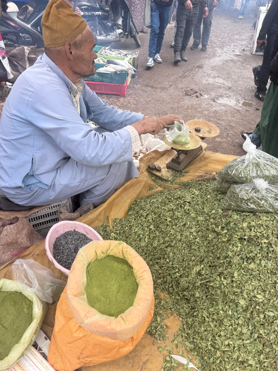 Un marchand pesant menthe séchée et henné sur une balance en laiton