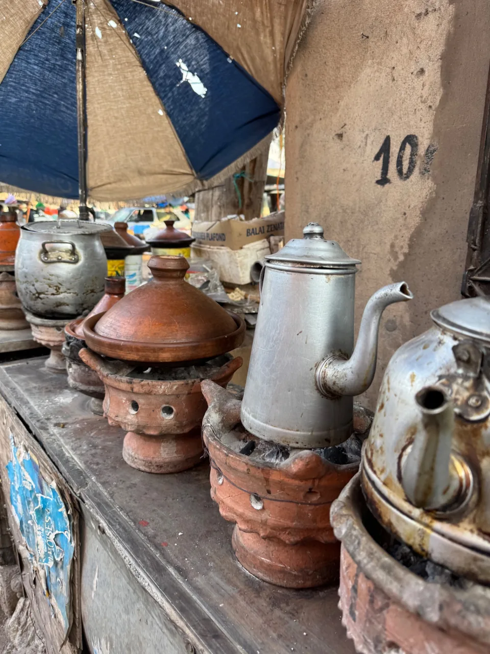 Théières et tajines en terre cuite mijotant sur des braseros au souk