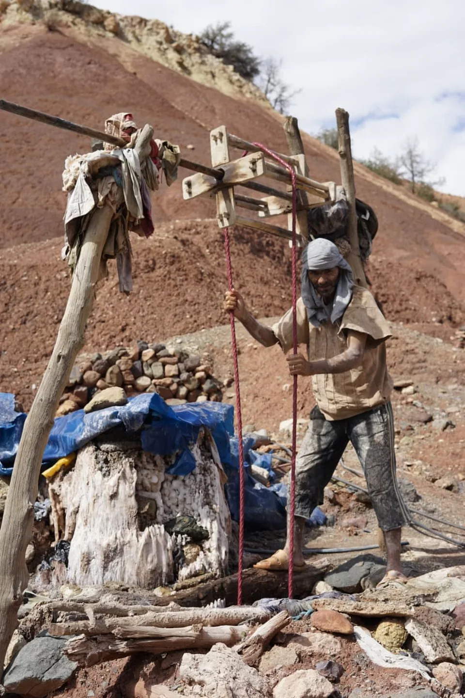 A salt worker drawing brine from a spring well by hand at Marigha