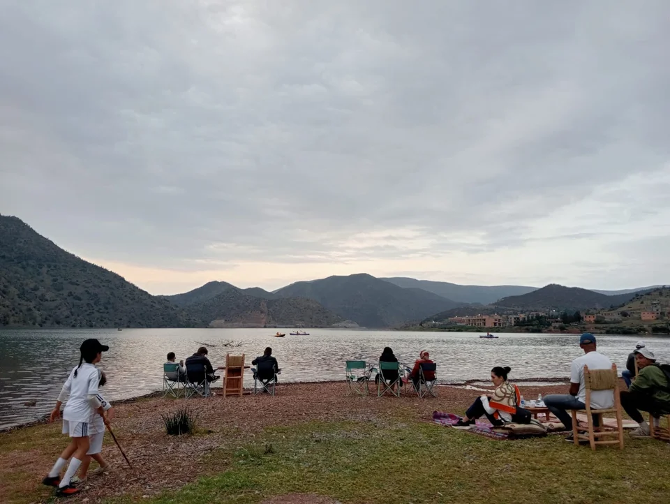 Des familles assises au bord de l'eau au crépuscule tandis que des kayaks traversent le barrage