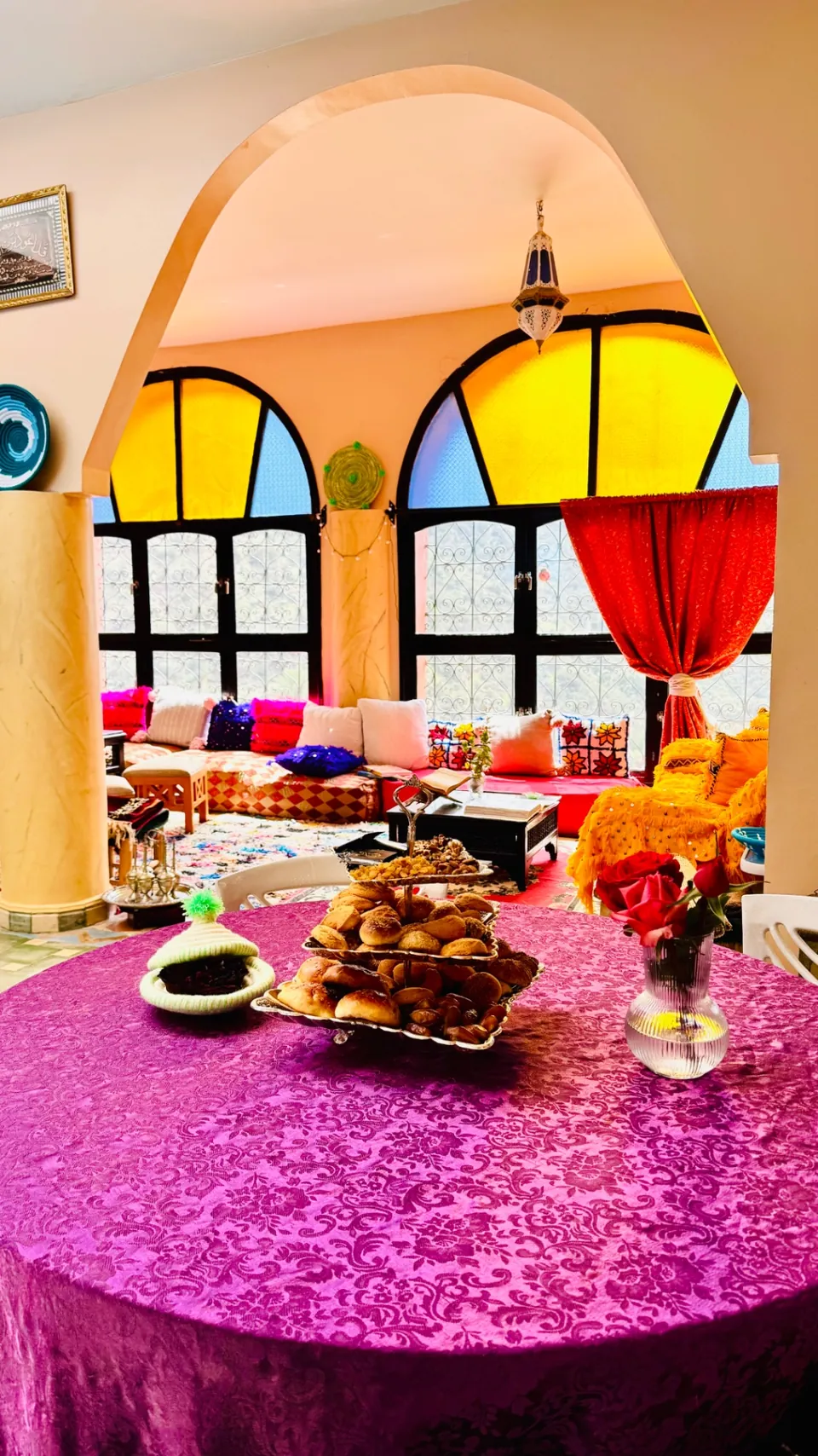 Moroccan pastries and roses on the salon table, the stained-glass arches beyond
