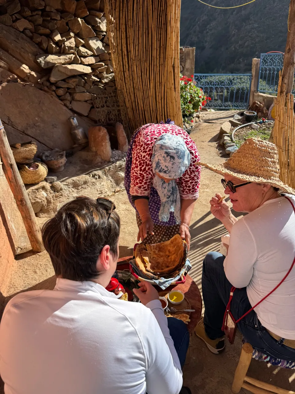 A village cook serving warm Tanort bread to guests in the courtyard